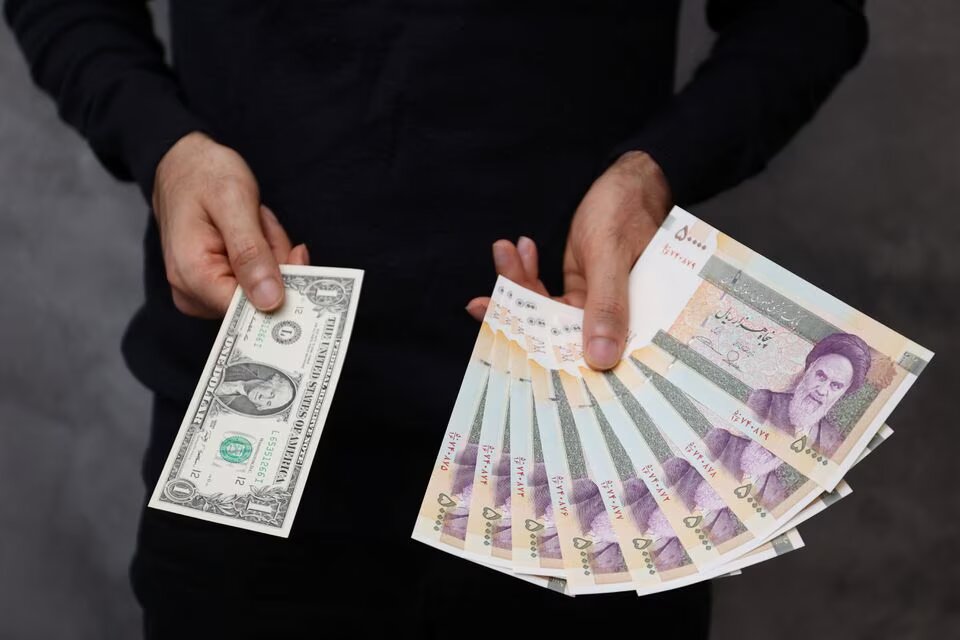 A currency dealer poses for a photo with a US one dollar bill and the amount being given when converting it into Iranian rials in an exchange shop in Tehran, Iran on December 25, 2022. Majid Asgaripour/WANA (West Asia News Agency) via REUTERS
