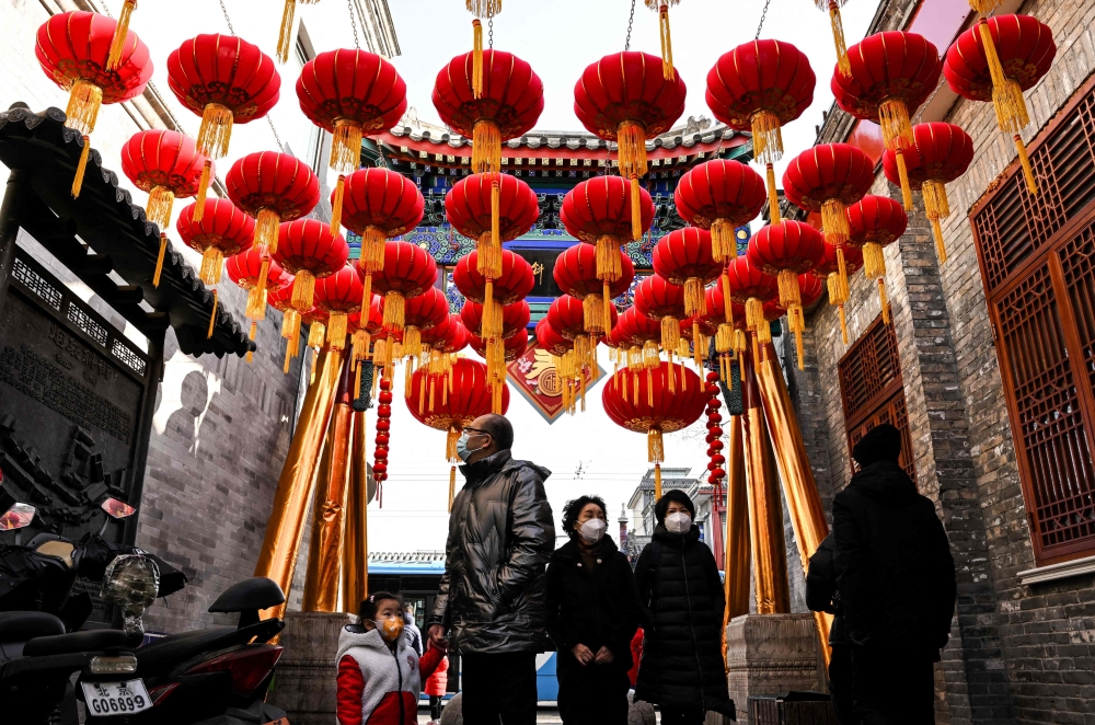 People walk under lanterns along an alley ahead of the lunar new year in Beijing on January 21, 2023. (Photo by Noel CELIS / AFP)