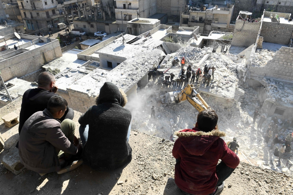 People watch as rescuers sift through the rubble of a building that collapsed in the the northern Syrian city of Aleppo on January 22, 2023.(AFP)