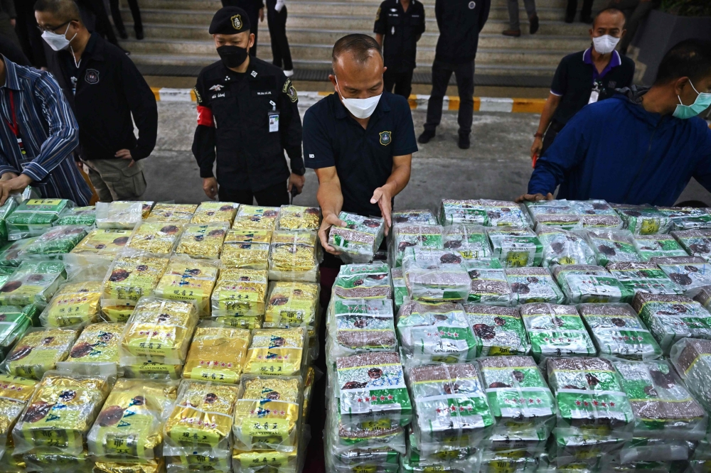 Thai policemen display packages of crystal methamphetamine before a press conference at the Narcotics Suppression Bureau in Bangkok on January 24, 2023. (Photo by Lillian Suwanrumpha / AFP)