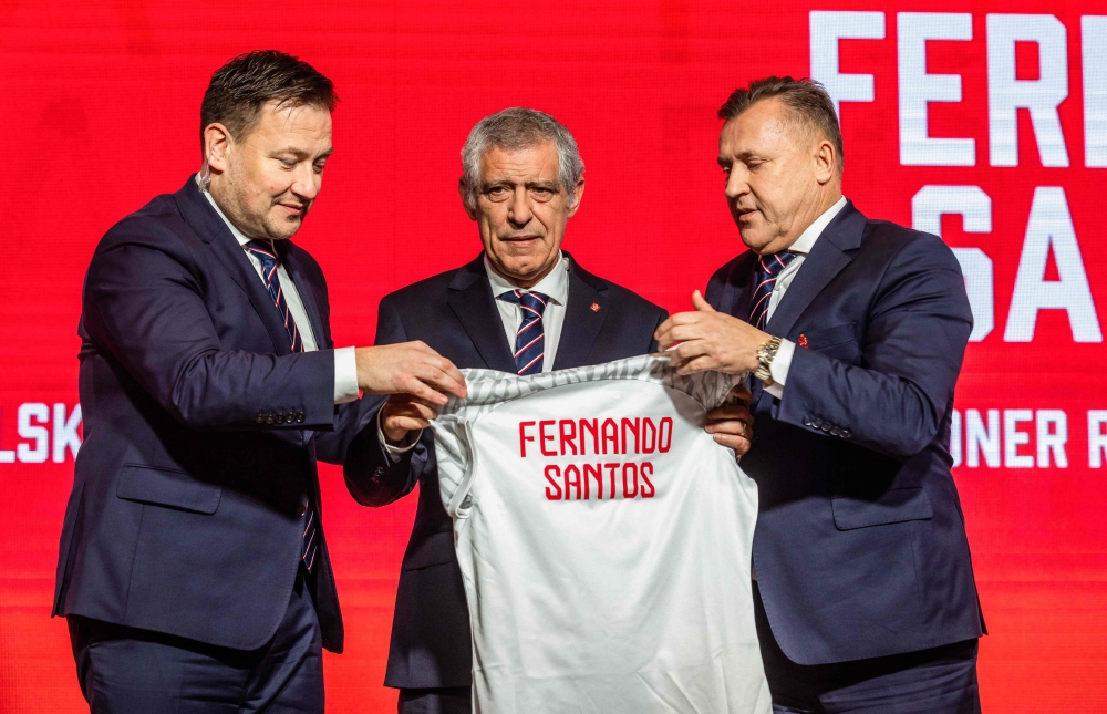 Newly appointed head coach of the Polish national football team Fernando Santos (centre), the secretary general of Polish Football Association Lukasz Wachowski (left) and the president of the Polish Football Association Cezary Kulesza pose with a shirt bearing the name of Fernando Santos during his presentation to the press at the national stadium in Warsaw, on January 24, 2023. (Photo by Wojtek RADWANSKI / AFP)