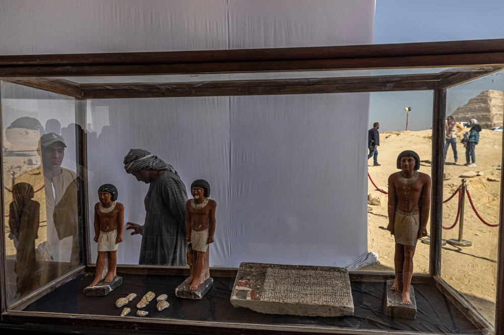 Workers stand behind a collection of pharaoh statues during a press conference at the Saqqara archaeological site, where a gold-laced mummy and four tombs including of an ancient king's 