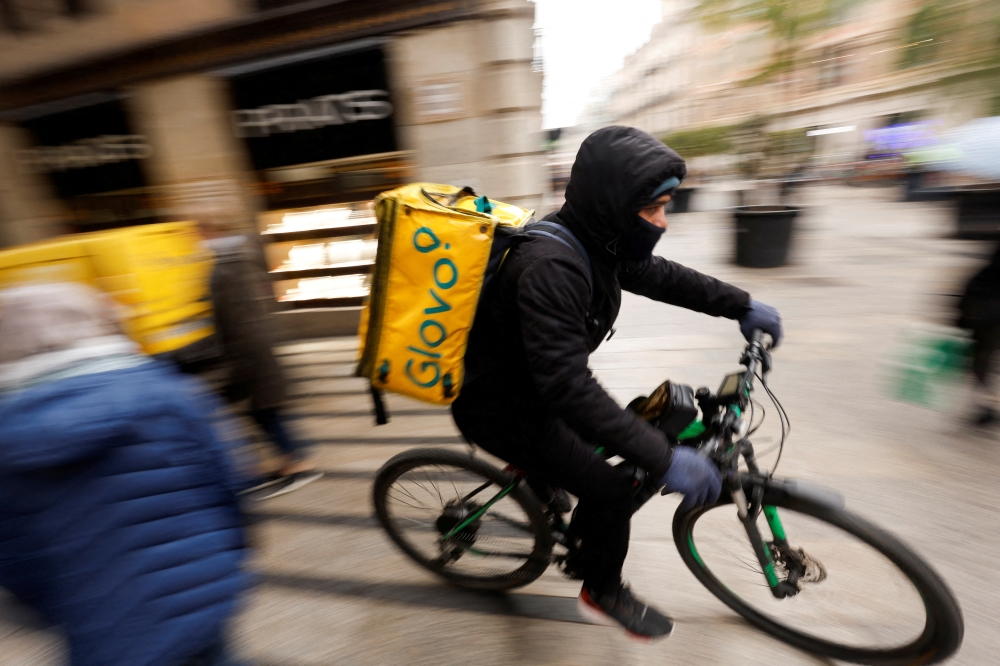 A Glovo delivery rider passes by a pedestrian area in Barcelona, Spain, January 24, 2023. REUTERS/Albert Gea/File Photo