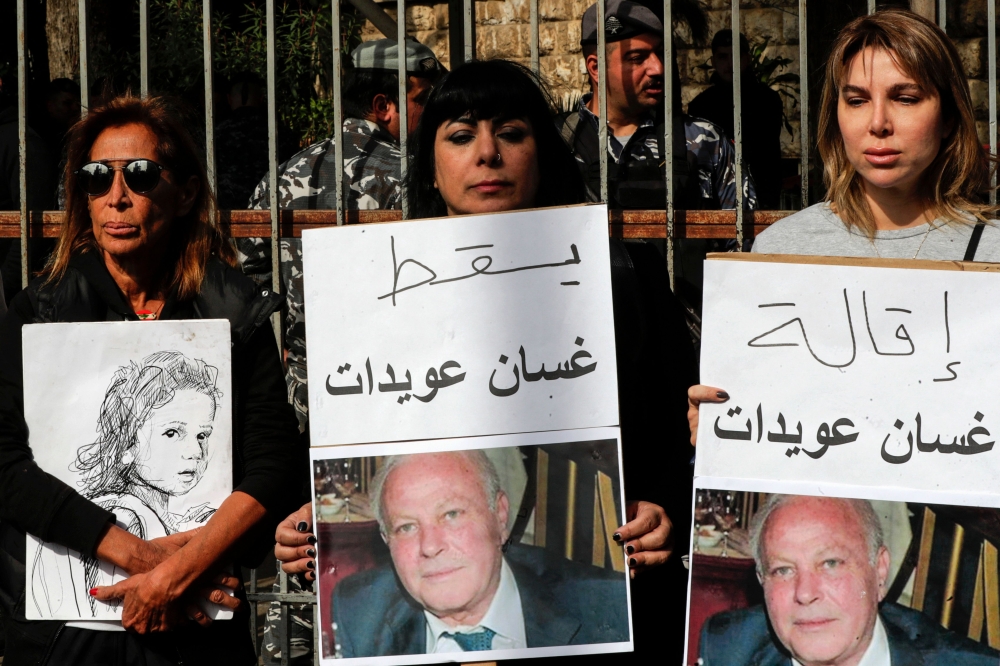 Lebanese demonstrators lift placards demanding top prosecutor Ghassan Oueidat be discharged and held accountable for the 2020 port blast, during a rally in the capital Beirut on January 28, 2023. - The judge leading the investigation into the deadly 2020 port explosion, charged on January 22 several powerful figures, including Oueidat, over the blast, reviving a probe that was suspended for over a year amid vehement political and legal pushback. (Photo by ANWAR AMRO / AFP)