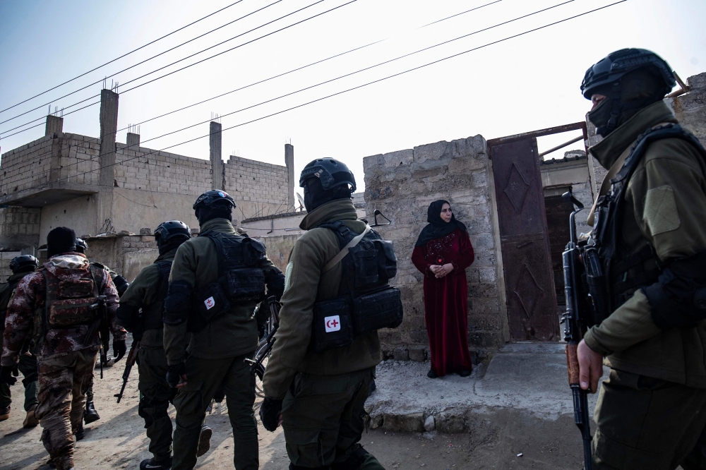 Syrian Kurdish Asayish security forces walks past a house during a raid against suspected Islamic State group fighters in Raqa, the jihadist group's former defacto capital in Syria, on January 29, 2023.  (Photo by Delil SOULEIMAN / AFP)