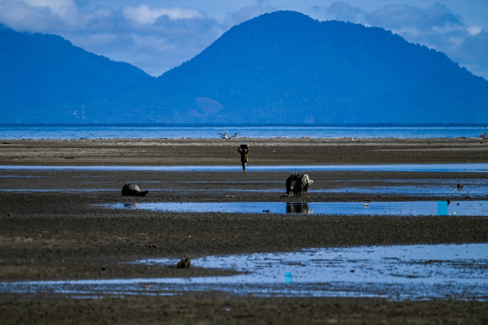 A woman walks home after fishing at a beach in Peukan Bada in Indonesia's Aceh province on February 1, 2023. (Photo by CHAIDEER MAHYUDDIN / AFP)
