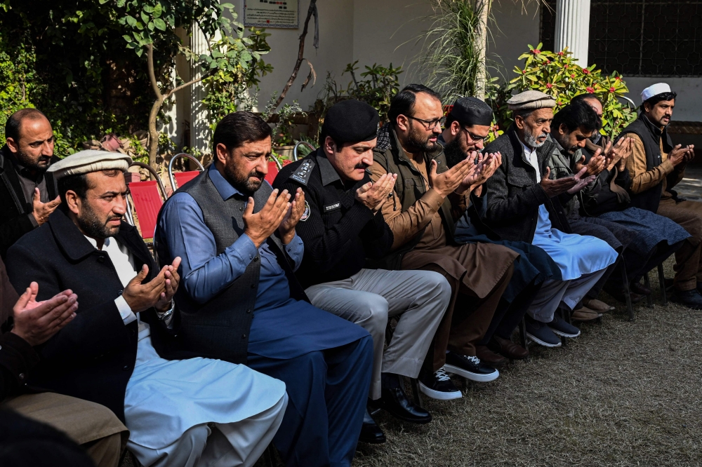 Relatives and police officials pray for a police officer Irfan Khan who was killed in a mosque suicide blast inside the police headquarters, during a condolence meeting at his residence in Peshawar on February 1, 2023. - A suicide blast at a mosque inside a Pakistan police headquarters was a targeted revenge attack, a police chief said, as rescue efforts ended with the death toll standing at 100. (Photo by Abdul MAJEED / AFP)