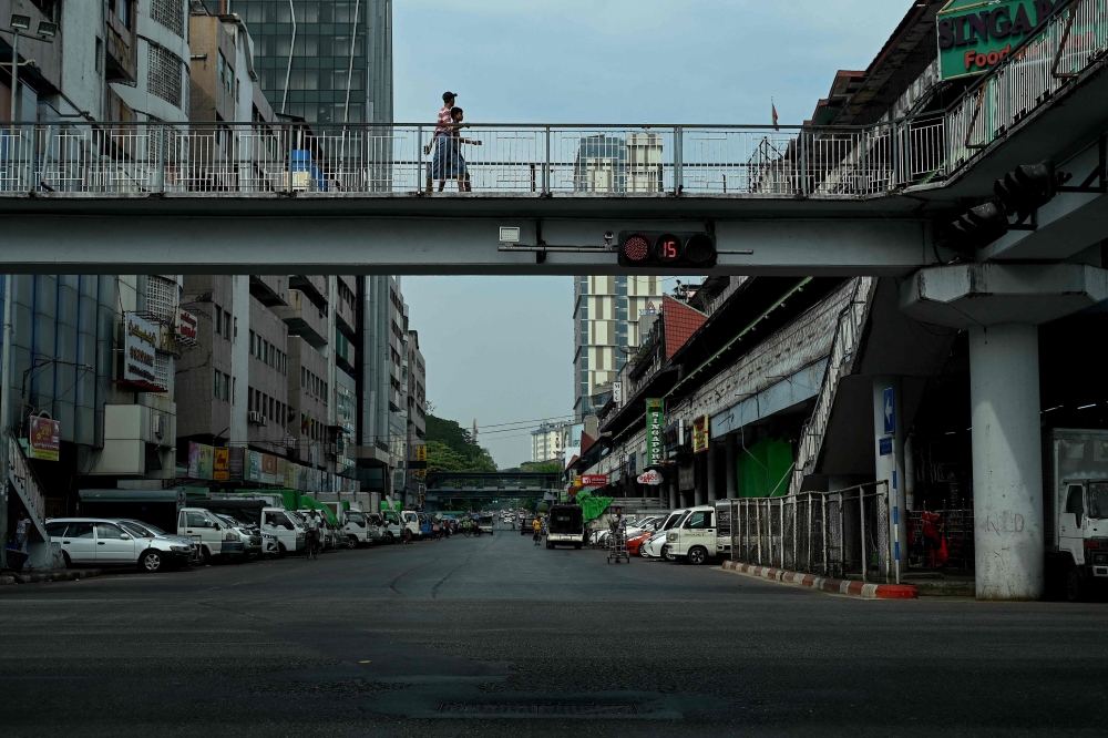 People walk past on a bridge an almost empty street during a 