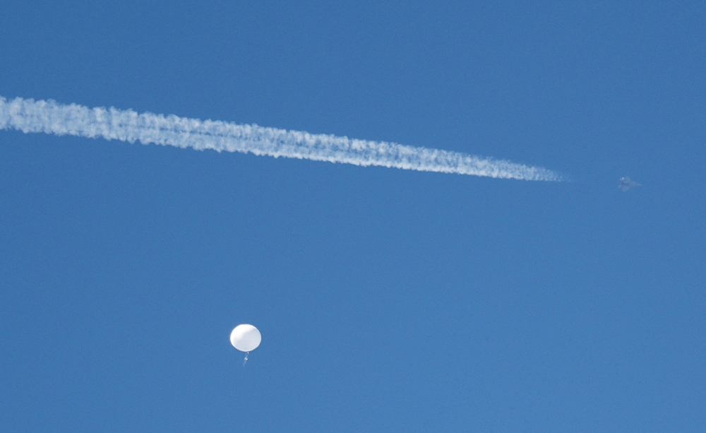 A jet flies by a suspected Chinese spy balloon as it floats off the coast in Surfside Beach, South Carolina, US on February 4, 2023. REUTERS/Randall Hill/File Photo