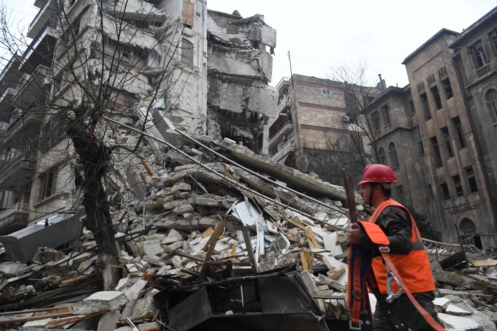 A member of a rescue team walks with his tools towards a collapsed building following an earthquake in Aleppo on February 6, 2023. Photo by AFP