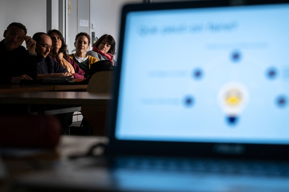 Teachers are seen behind a laptop during a workshop on ChatGpt bot organised for by the School Media Service (SEM) of the Public education of the Swiss canton of Geneva, on February 1, 2023. (Photo by Fabrice COFFRINI / AFP)