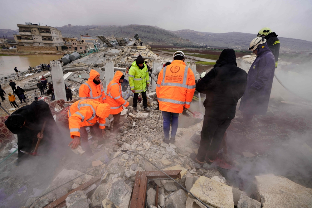 White Helmet rescue workers search for victims and survivors in the rubble of collapsed buildings, following an earthquake in the town of Sarmada in the countryside of the northwestern Syrian Idlib province, early on February 6, 2023.  (Photo by MUHAMMAD HAJ KADOUR / AFP)