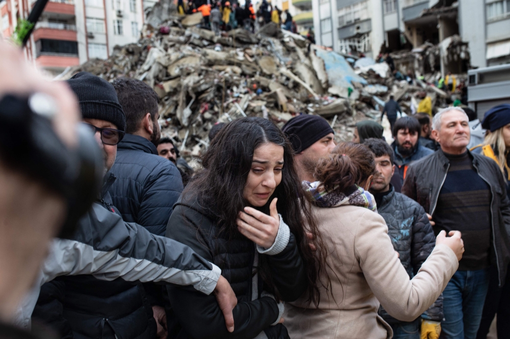 A woman reacts as rescuers search for survivors through the rubble of collapsed buildings in Adana, on February 6, 2023. Photo by Can EROK / AFP
