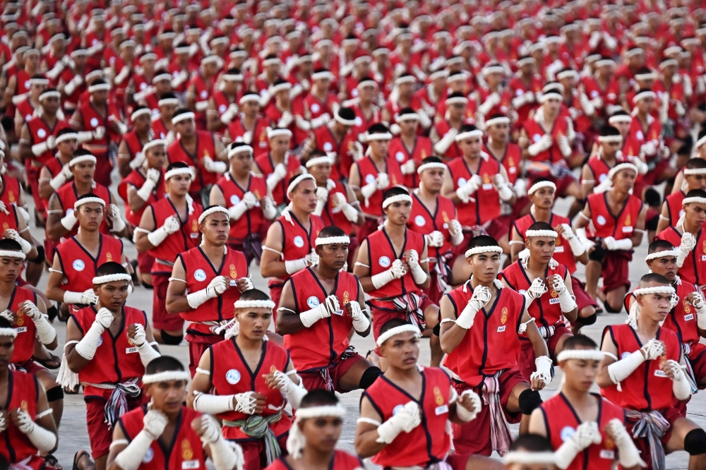 Muay Thai fighters perform the traditional Wai Kru ceremony during a festival for the Thai martial art in Rajabhakti Park in Hua Hin on February 6, 2023, as some 3,360 exponents gathered in an attempt to break the Guinness World Record for the most people taking part in the Wai Kru ritual at once. (Photo by Lillian Suwanrumpha / AFP)