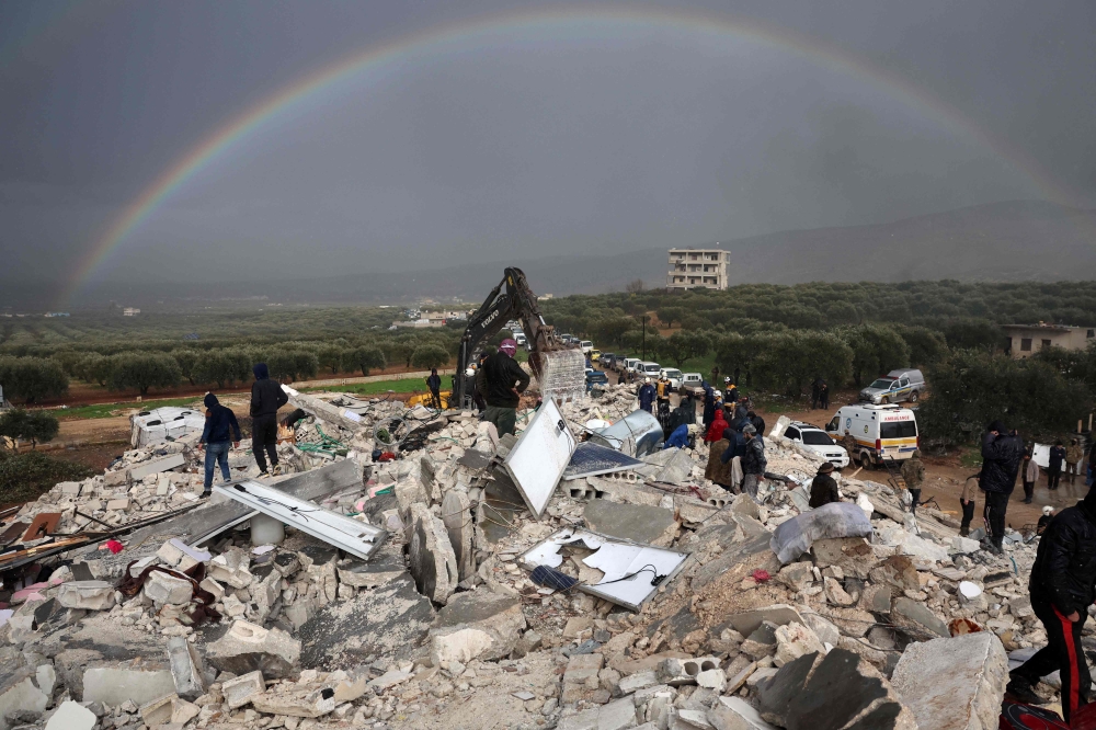 Residents search for victims and survivors amidst the rubble of collapsed buildings in the village of Besnaya in Syria, on February 6, 2022. (Photo by Omar Haj Kadour / AFP)
