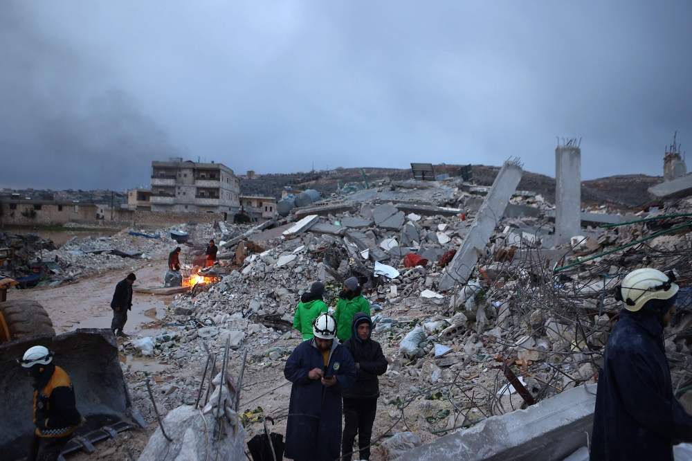 Syrian rescue workers gather amidst collapsed buildings on February 6, 2022 in the town of Sarmada, in Syria's rebel-held northwestern Idlib province, as a search operation continues following a deadly earthquake. - At least 1,400 people were killed and 3,411 injured across Syria today in an earthquake that had its epicentre in southwestern Turkey, the government and rescuers said. (Photo by AAREF WATAD / AFP)
