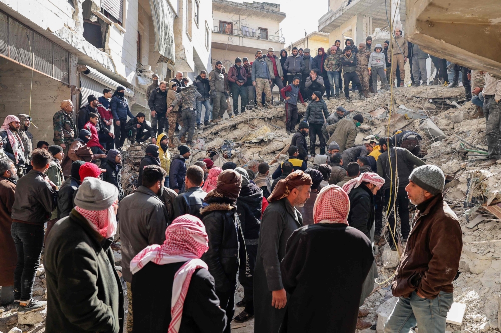 Rescuers search the rubble of buildings for casualties and survivors in the village of Salqin in Syria's rebel-held northwestern Idlib province at the border with Turkey following an earthquake, on February 7, 2023. (Photo by Omar HAJ KADOUR / AFP)