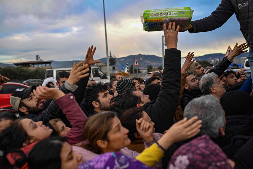 Earthquake survivors gather to collect supplies at a diaper distribution in Hatay on February 7, 2023, a day after a 7,8-magnitude earthquake struck Turkey's southeast. (Photo by BULENT KILIC / AFP)