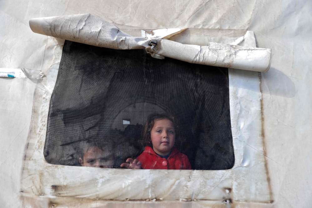 Syrian children look out of the window of a tent window at an emergency shelter in the center of the city of Maarat Misrin, in the rebel-held northern part of the northwestern Idlib province one day after a deadly earthquake hit Syria and Turkey, on February 7, 2023. (Photo by Abdulaziz Ketaz / AFP)