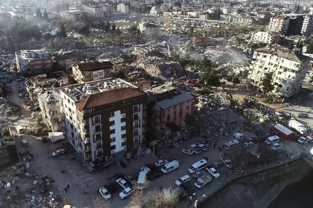 This aerial view shows a collapsed building during ongoing rescue searches in Hatay, southeastern Turkey, on February 9, 2023, two days after a strong earthquake struck the region. (Photo by DHA (Demiroren News Agency) / AFP)
