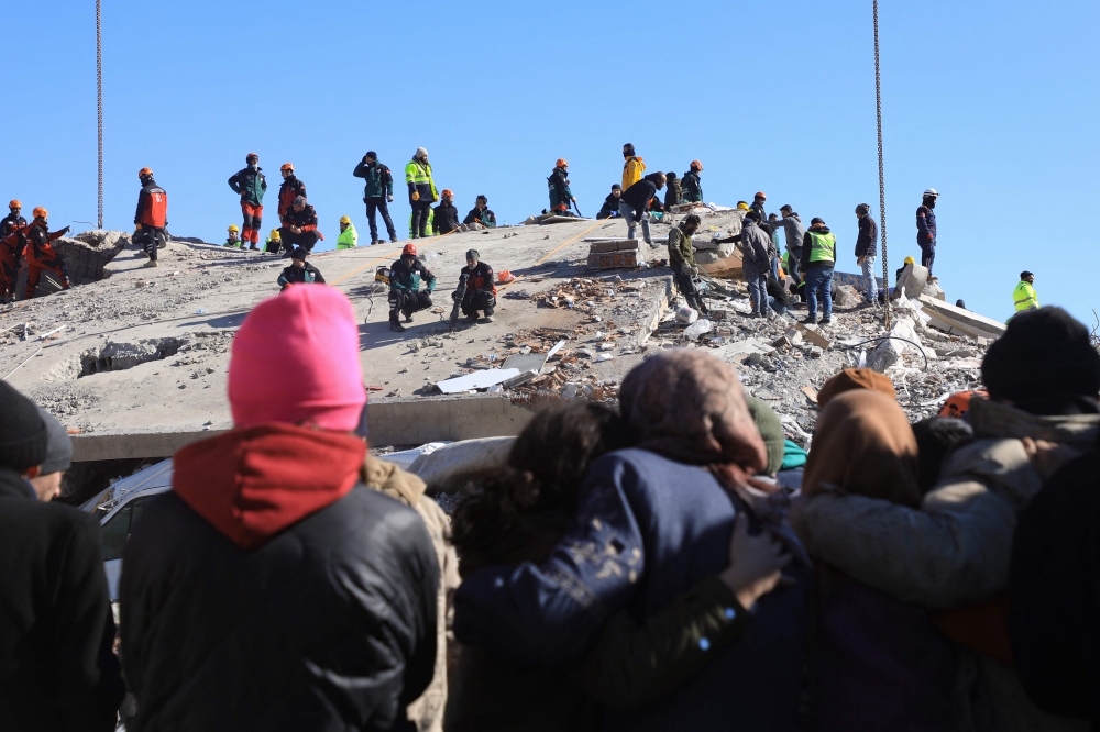 People watch as rescuers and civilians look for survivors under the rubble of collapsed buildings in Nurdagi, in the countryside of Gaziantep, on February 9, 2023, three days after a deadly earthquake that hit Turkey and Syria. Photo by Zein Al RIFAI / AFP