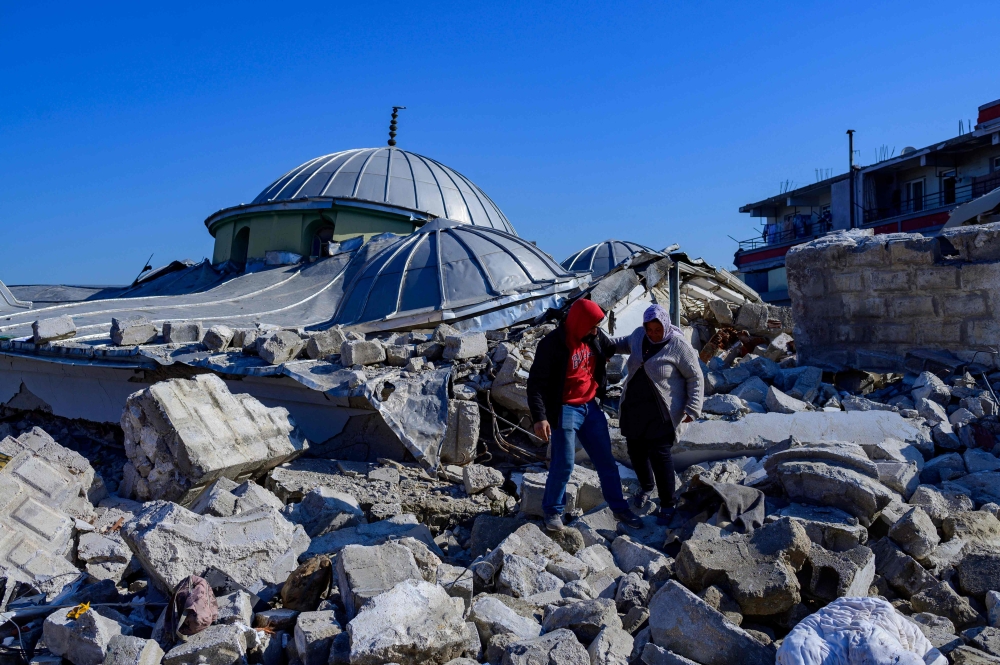 Local residents walk in the rubble of a destroyed mosque in Hatay, on February 10, 2023, after the 7.8 magnitude earthquake that killed over 20,000 people. (Photo by Yasin AKGUL / AFP)
 