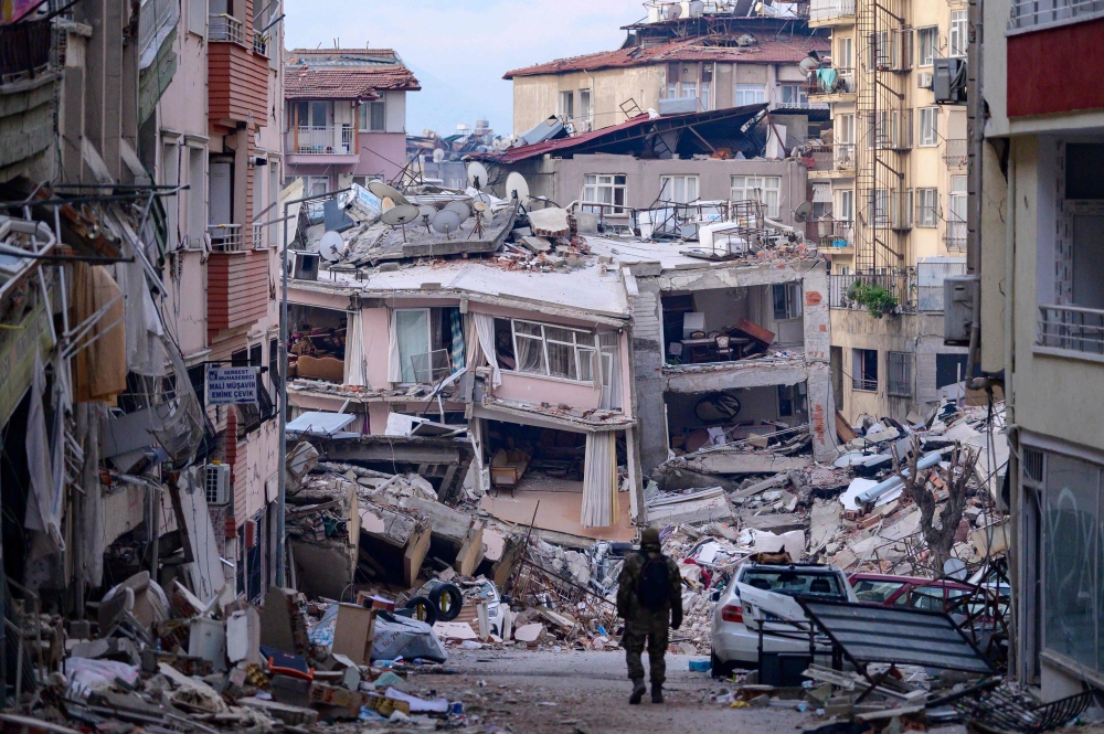 A Turkish soldier walks among destroyed buildings in Hatay, on February 12, 2023, after a 7.8-magnitude earthquake struck the country's south-east. (Photo by Yasin Akgul / AFP)