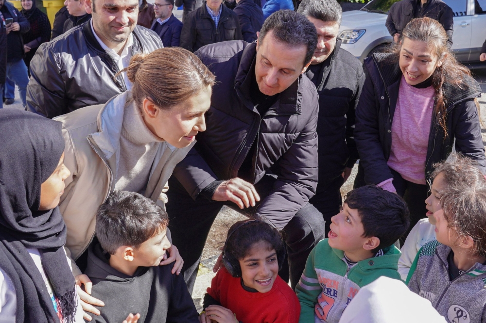 A handout picture released by the official Syrian Arab News Agency (SANA) on February 11, 2023, shows Syria's President Bashar al-Assad (right) and first lady Asma al-Assad (left) visiting families affected by the earthquake, at the Basil Al-Assad Center for Educational Training in Latakia, on February 11, 2023. (Photo by SANA / AFP) 