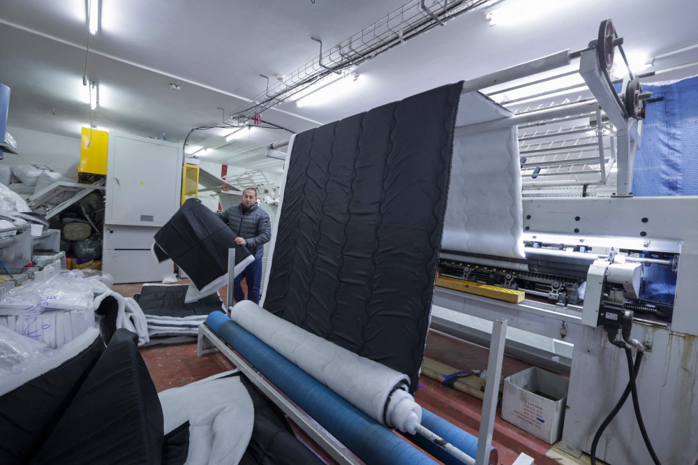 An employee works on an order of custom-made cold weather sleeping bags to be donated for earthquake relief, at the Palestinian Super-Tex al-Saafin textile factory in Hebron city in the occupied West Bank, on February 14, 2023. (Photo by HAZEM BADER / AFP)