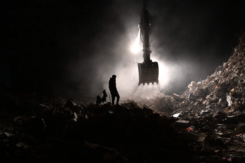 A local resident, whose loved ones are still under the rubble, wander near the collapsed buildings in Hatay on February 14, 2023. (Photo by Bulent Kilic / AFP)