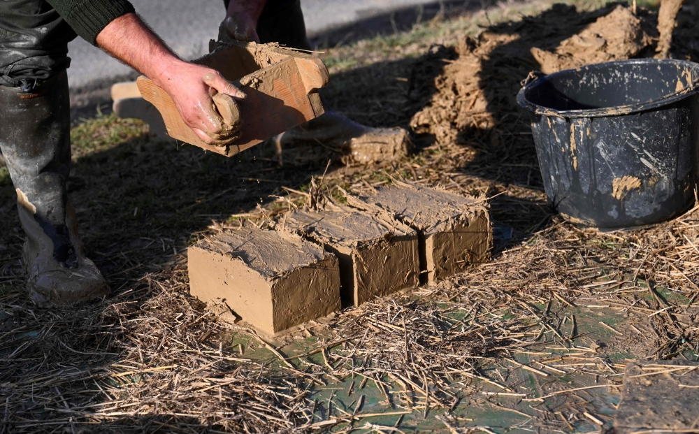 Master builder Janos Gaspar explains the making of bricks of a mud-brick house in Acs, northwestern Hungary, on November 25, 2022. Photo by ATTILA KISBENEDEK / AFP