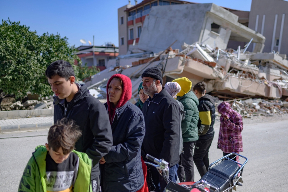 Residents wait in a queue outside a bakery that gives out free bread in Samandag, south of Hatay on February 16, 2023, ten days after a 7.8-magnitude struck the border region of turkey and Syria. (Photo by Yasin Akgul / AFP)