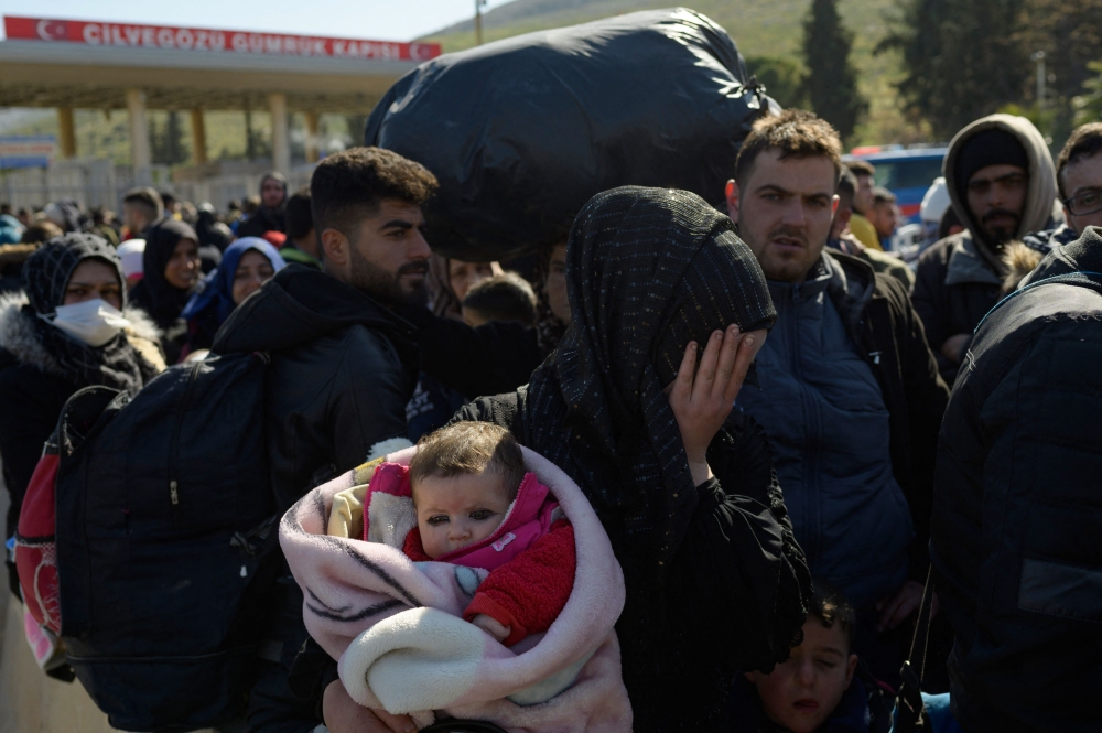Syrian residents of Hatay city wait to cross the Turkish-Syrian border after they were affected by the 7.8-magnitude earthquake that struck the region nearly two weeks ago, at Cilvegozu border gate on February 17, 2023. (Photo by Yasin Akgul / AFP)