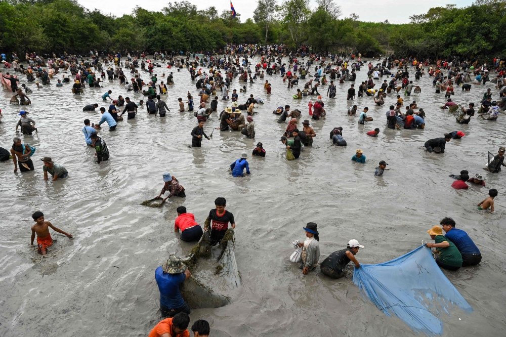Villagers catch fish during the annual fish-catching ceremony at the Choam Krovean commune in Tboung Khmum province on February 18, 2023. (Photo by Tang Chhin Sothy / AFP)