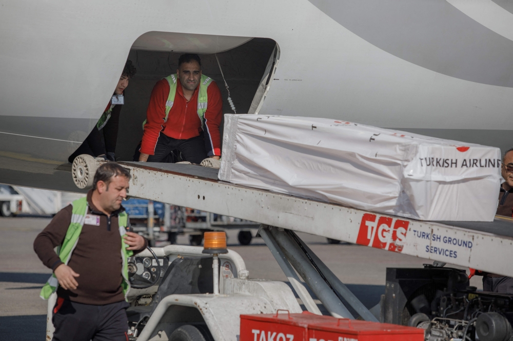 The coffin containing the body of former Ghana international football player Christian Atsu is loaded into an airplane bound for Ghana, at Adana airport in southern Turkey, February 18, 2023. (Photo by CAN EROK / AFP) 