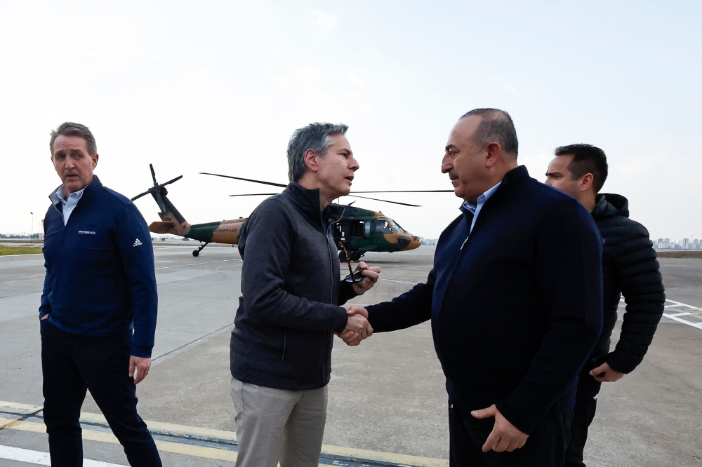 US Secretary of State Antony Blinken (center) shakes hands with Turkish Foreign Minister Mevlut Cavusoglu after a helicopter tour of earthquake stricken areas on February 19, 2023, during an official visit after a 7,8-magnitude earthquake struck Turkey's south-east.  (Photo by CLODAGH KILCOYNE / POOL / AFP)
