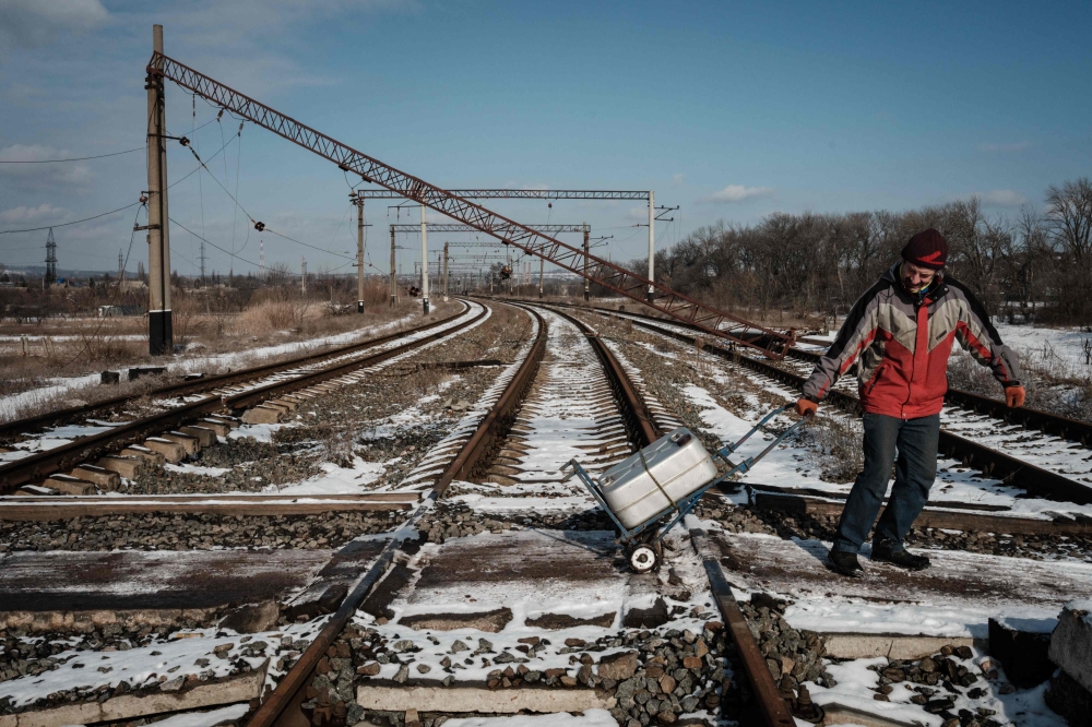 Volodymyr, 55, a gas supply system operator, pulls a trolley with a container holding 40 liters of water after fetching it from a well, in Siversk on February 17, 2023, amid the Russian invasion of Ukraine. (Photo by YASUYOSHI CHIBA / AFP)