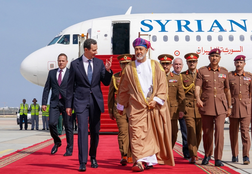 A handout picture released by the official Syrian Arab News Agency (SANA) shows President Bashar al-Assad (left) being welcomed by Oman's Sultan Haitham bin Tariq al-Said in Muscat on February 20, 2023. (AFP) 