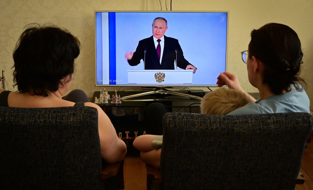 A family watches a TV broadcast of Russian President Vladimir Putin's annual state of the nation address in Moscow on February 21, 2023. (Photo by Yuri Kadobnov/ AFP)
 