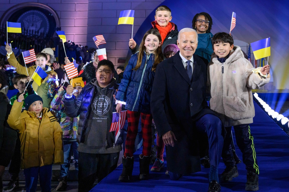 US President Joe Biden stands amid children cheering with US, Polish and Ukrainian flags after he delivered a speech in front of the Royal Warsaw Castle Gardens in Warsaw, Poland, on February 21, 2023. (Photo by Mandel Ngan / AFP)