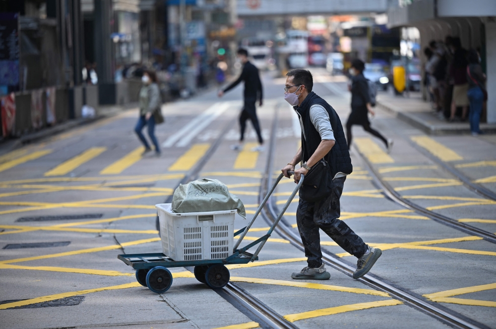 This photo taken on February 21, 2023 shows a vendor crossing a street in Central district of Hong Kong. - Hong Kong痴 finance chief unveiled a HK$761 billion ($97 billion) budget on February 22, plunging into the coffers to foot the bill for the recession-hit city痴 post-Covid recovery. (Photo by Peter PARKS / AFP)