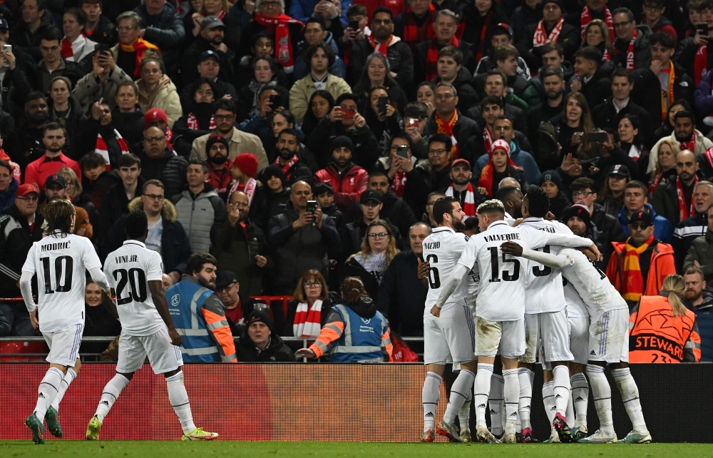 Real Madrid's French forward Karim Benzema is mobbed by teammates after scoring the team's fourth goal during the UEFA Champions League last 16 first leg football match between Liverpool and Real Madrid at Anfield in Liverpool, north west England on February 21, 2023. (Photo by Paul ELLIS / AFP)