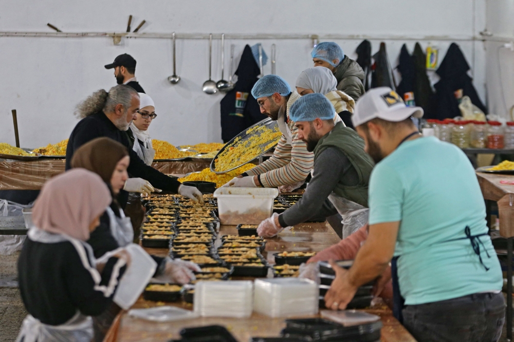 Volunteers prepare food to serve people affected by the 7.8-magnitude quake, in the government-held northern city of Aleppo on February 21, 2023. (Photo by LOUAI BESHARA / AFP)