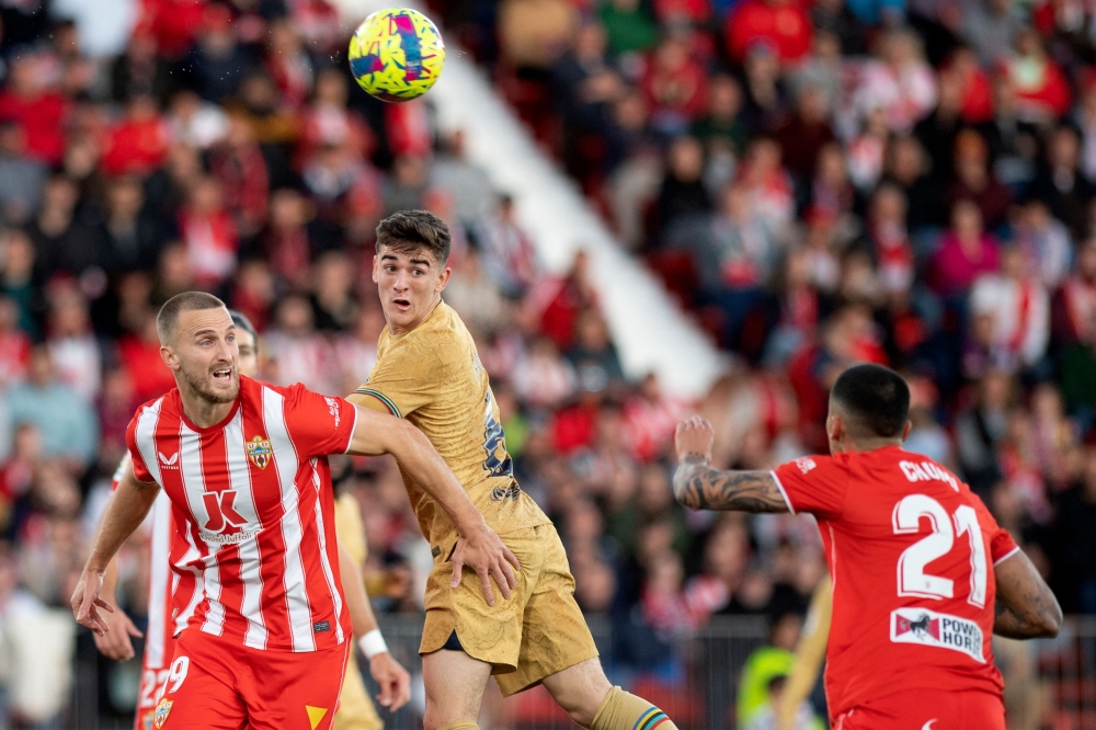 Barcelona's midfielder Gavi (centre) fights for the ball with Almeria's Brazilian defender Rodrigo Ely (L) and Almeria's Spanish defender Chumi during the Spanish League match between UD Almeria and FC Barcelona at the Municipal Stadium of the Mediterranean Games in Almeria, on February 26, 2023. (Photo by JORGE GUERRERO / AFP)
