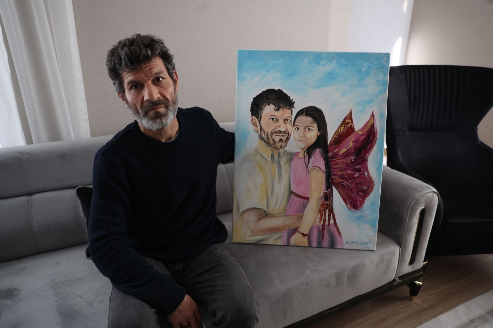 Turkish father Mesut Hancer, poses and holds a painting representing him and his daughter Irmak in his appartment in Ankara on February 25, 2023, as his family tries to rebuild, after losing their daughter Irmak, 15 years old, in the earthquake that devastated the southeastern region of Turkey. Photo by Adem ALTAN / AFP