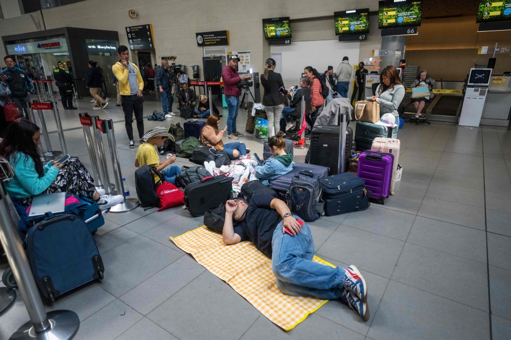 People lie on the floor after their flights were cancelled at the El Dorado international airport in Bogota on February 28, 2023. (Photo by Juan Barreto / AFP)