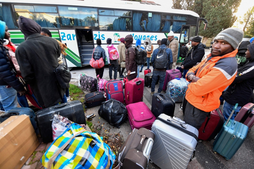 Sub-Saharan migrants queue to board a bus with their belongings as they head to a repatriation flight, leaving Tunis for their countries of origin on March 4, 2023. (Photo by Fethi Belaid / AFP)
 