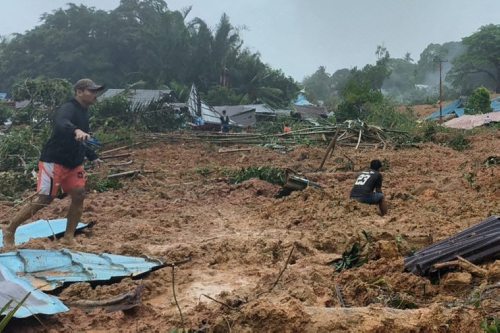 This handout photo taken and released on March 6, 2023 by the BNPB (National Disaster Management Agency) shows people inspecting the damage at a village that was hit by landslides in Natuna in Indonesia's Riau Province. (Photo by Handout / BNPB / AFP) 