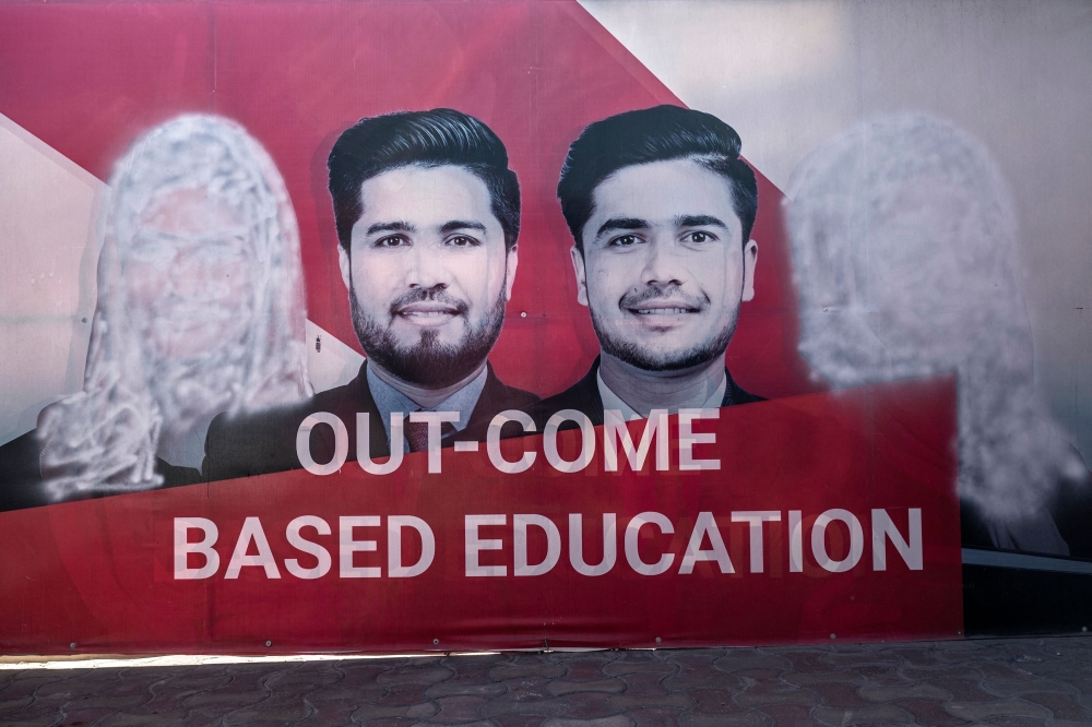 A banner seen with images of women defaced using spray paint are pictured inside a private university after the universities were reopened in Kabul on March 6, 2023. - Male students trickled back to their classes on March 6 after Afghan universities reopened following a winter break but women remain barred by Taliban authorities. (Photo by Wakil KOHSAR / AFP)