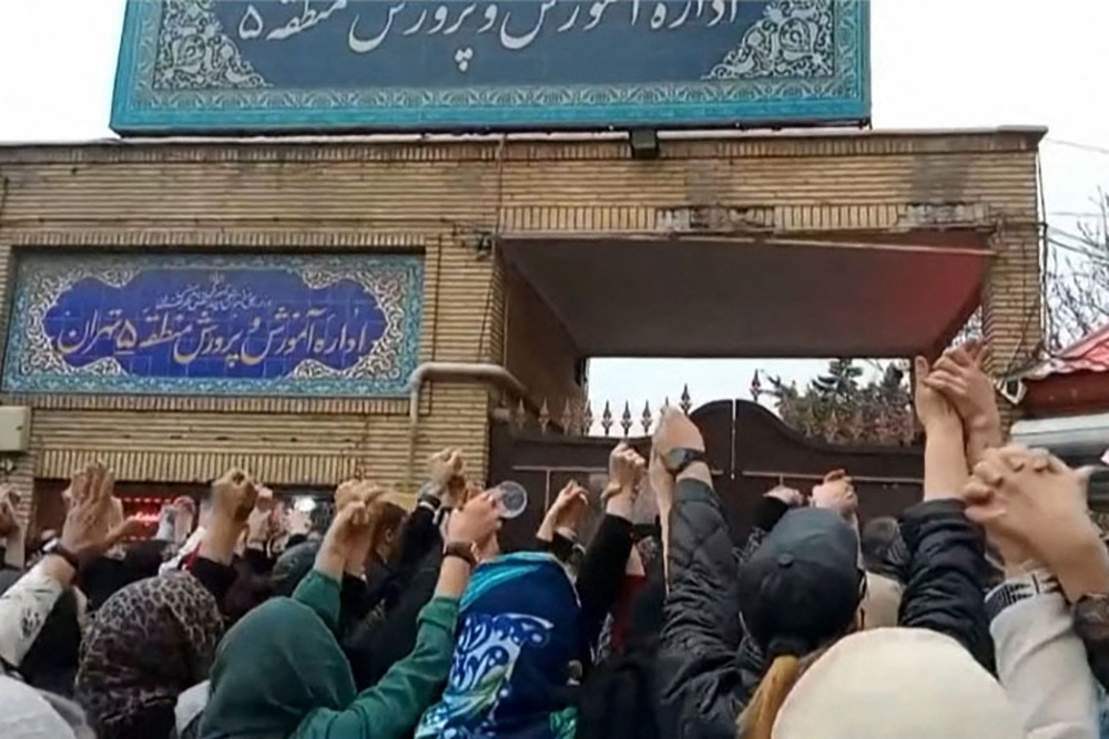 This grab taken from a UGC video made available on the ESN platform on March 4, 2023, shows families gathering and chanting slogans outside an education ministry building in Tehran, following poisoning attacks on students. (Photo by Anonymous/ESN / AFP) 

